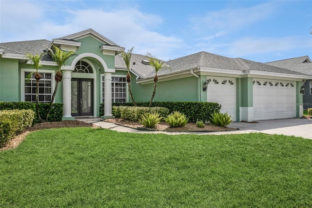 view of front facade with a front yard, roof with shingles, stucco siding, french doors, and a garage