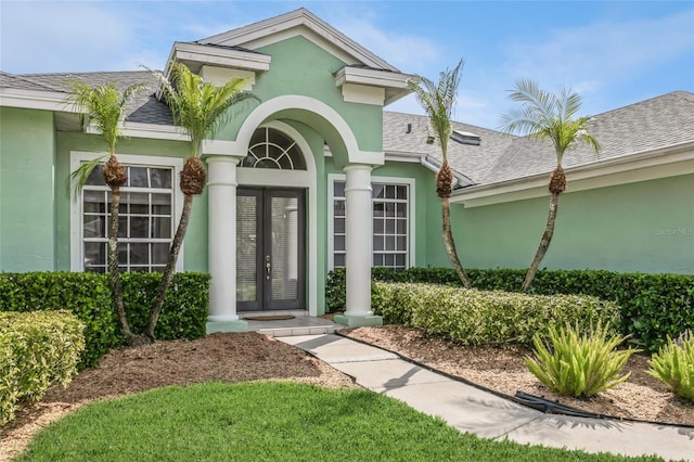 doorway to property with a shingled roof, french doors, and stucco siding