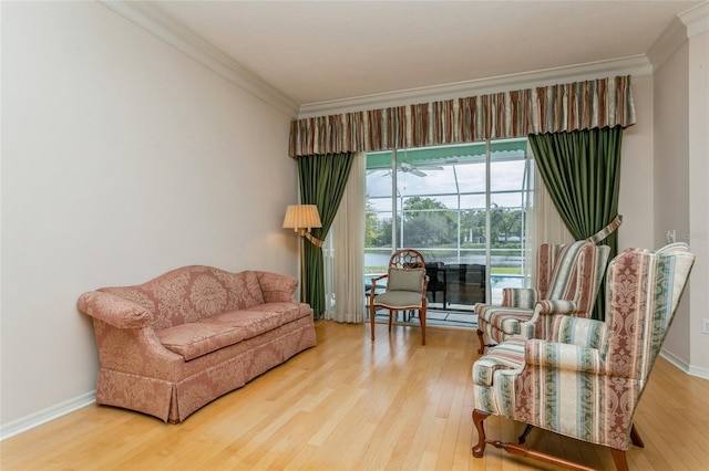 living area with wood finished floors, baseboards, and ornamental molding