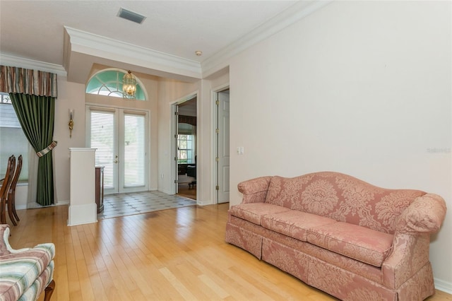 living room with a notable chandelier, light wood-style flooring, crown molding, and baseboards