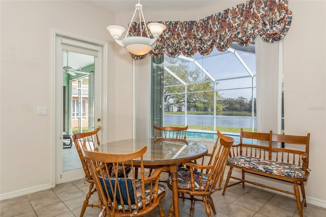 dining area with light tile patterned floors, baseboards, a water view, and a sunroom