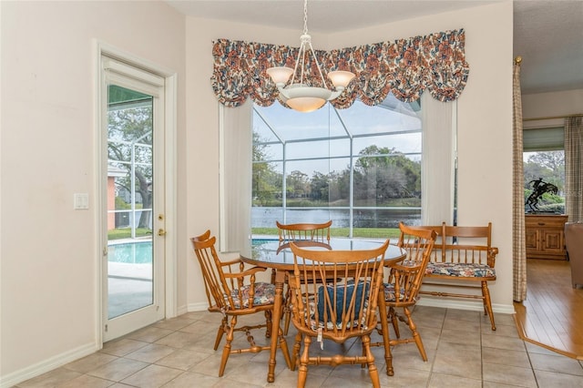 dining room with a wealth of natural light, an inviting chandelier, tile patterned floors, and baseboards