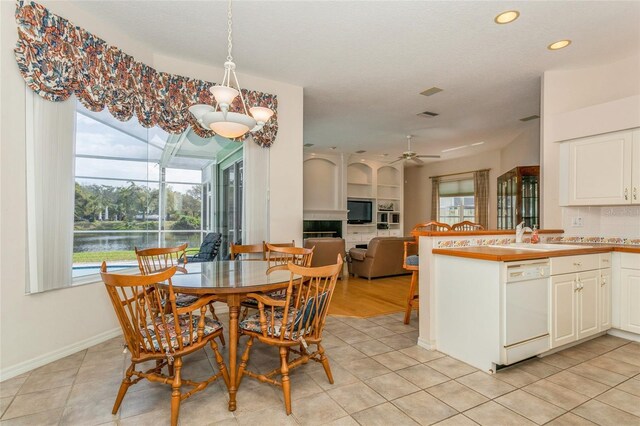 dining space featuring light tile patterned floors, plenty of natural light, and a water view