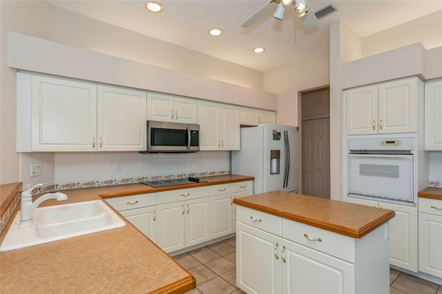 kitchen with a sink, white appliances, backsplash, and light tile patterned flooring