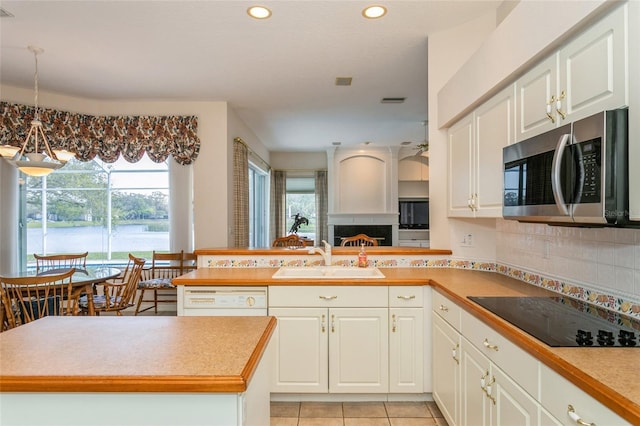 kitchen with a sink, stainless steel microwave, tasteful backsplash, black electric stovetop, and dishwasher