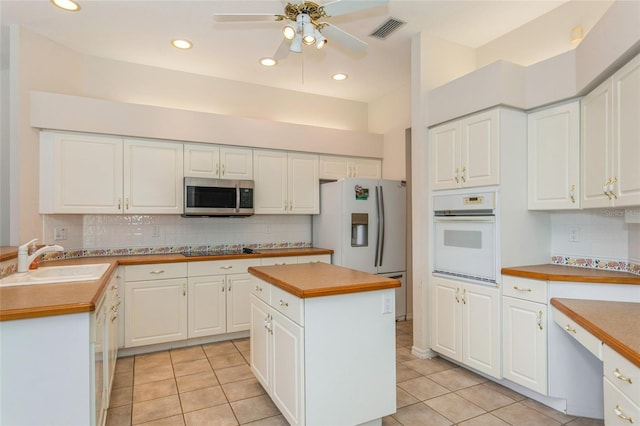 kitchen featuring white cabinetry, white appliances, light tile patterned floors, and a sink