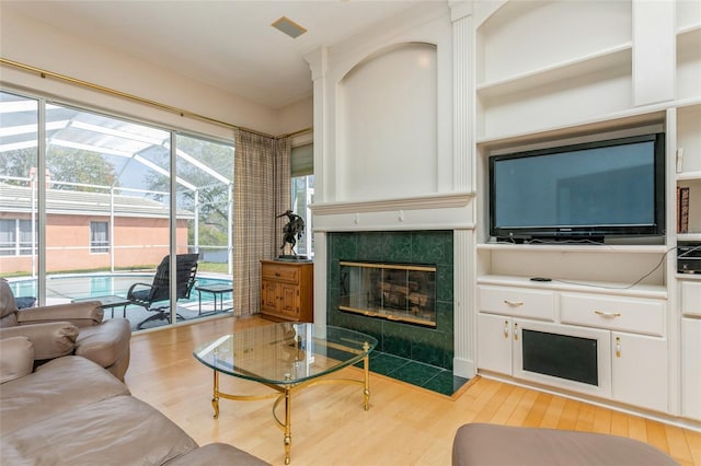 living room featuring visible vents, a sunroom, wood finished floors, and a tile fireplace