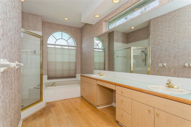 full bath featuring wallpapered walls, double vanity, a stall shower, and a sink