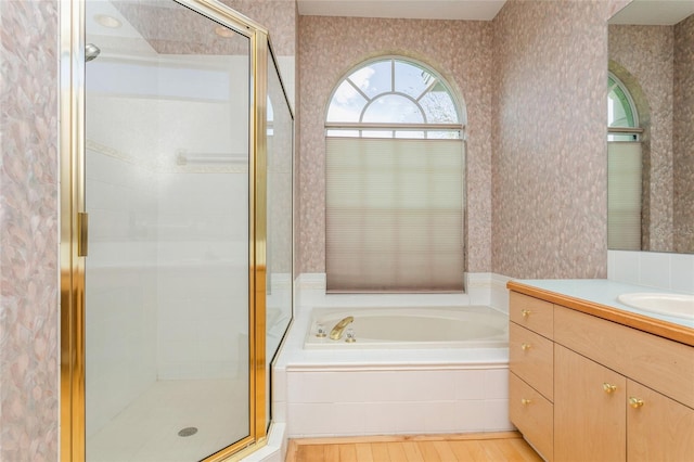 bathroom with a garden tub, a shower stall, and wallpapered walls