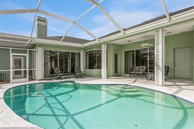 outdoor pool with glass enclosure, a patio area, and ceiling fan