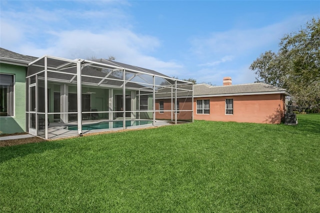 rear view of house featuring a yard, an outdoor pool, stucco siding, a chimney, and a lanai