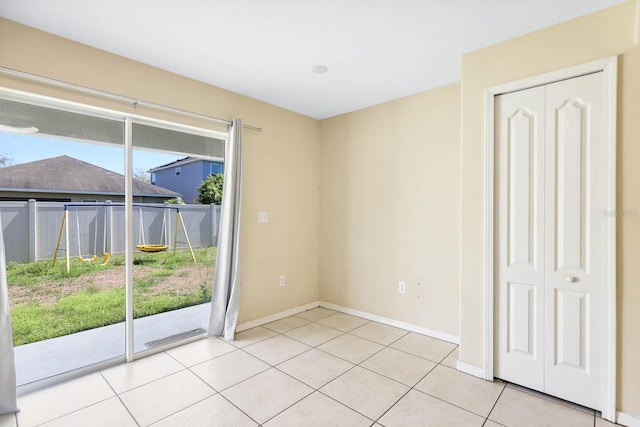 spare room featuring light tile patterned floors and baseboards