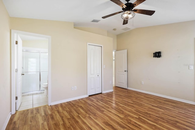 unfurnished bedroom with visible vents, lofted ceiling, light wood-style flooring, and ensuite bathroom