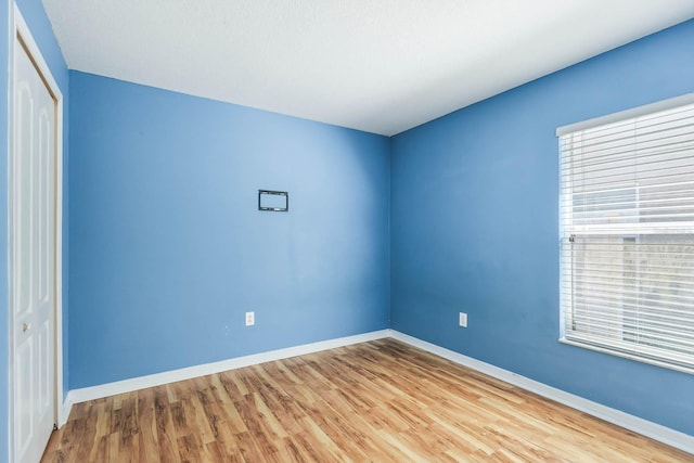 spare room featuring baseboards and wood finished floors