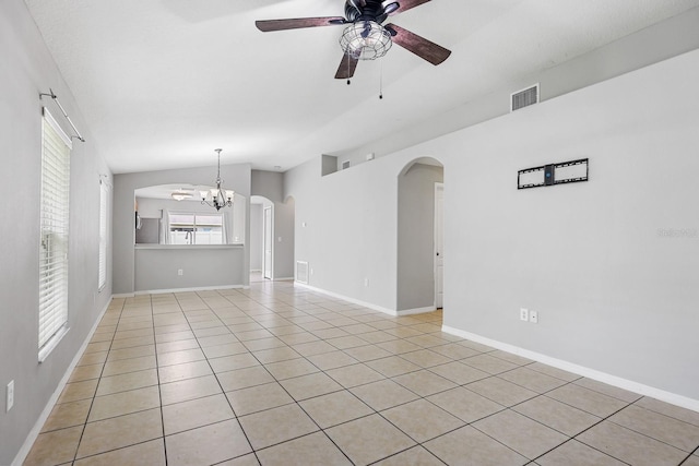 7233 Lumber Port Dr, Ruskin, FL 33573 - empty room with arched walkways, a ceiling fan, a chandelier, light tile patterned flooring, and vaulted ceiling