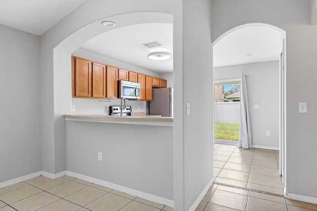 7233 Lumber Port Dr, Ruskin, FL 33573 - kitchen with appliances with stainless steel finishes, arched walkways, and light tile patterned floors