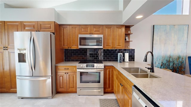 kitchen with brown cabinets, a sink, tasteful backsplash, appliances with stainless steel finishes, and light countertops