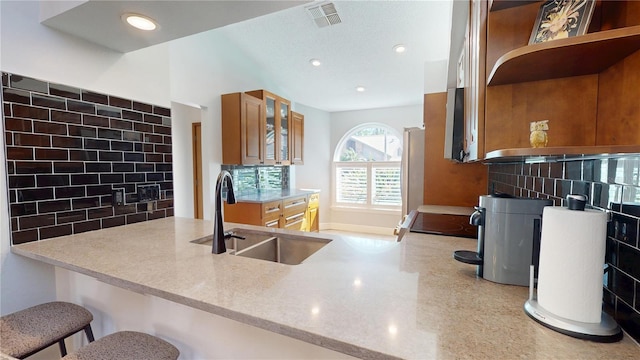 kitchen featuring a sink, open shelves, visible vents, and brown cabinetry