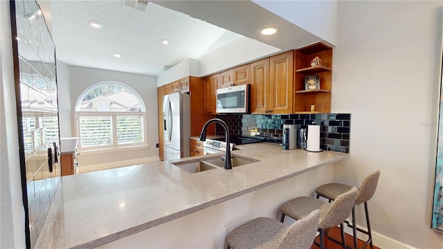 kitchen with visible vents, a sink, open shelves, stainless steel appliances, and decorative backsplash