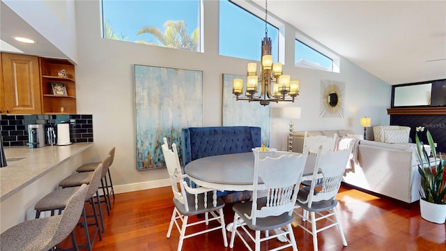 dining room featuring dark wood finished floors, a notable chandelier, baseboards, and high vaulted ceiling