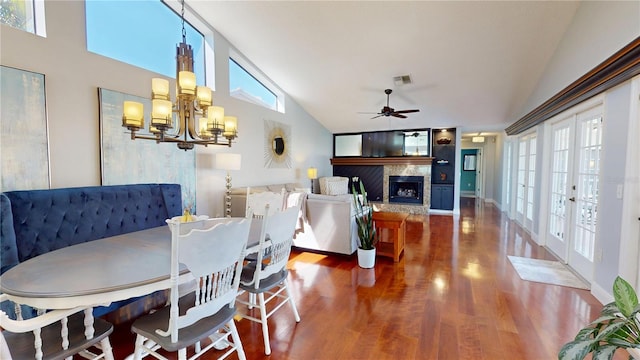 dining space featuring wood finished floors, ceiling fan with notable chandelier, a high end fireplace, and a healthy amount of sunlight