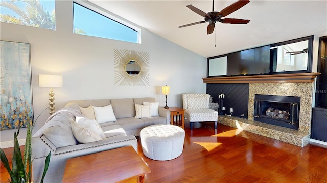 living area with baseboards, a premium fireplace, wood finished floors, high vaulted ceiling, and a ceiling fan