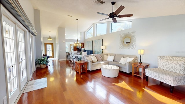 living area featuring visible vents, high vaulted ceiling, wood finished floors, and ceiling fan with notable chandelier