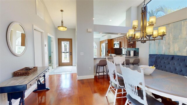 dining area with recessed lighting, baseboards, an inviting chandelier, and wood finished floors