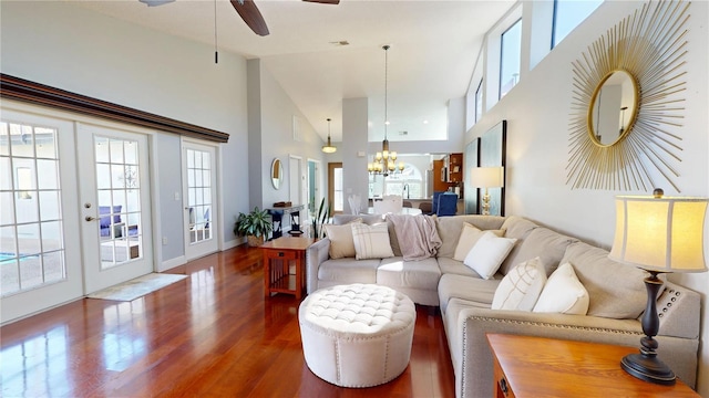 living room with baseboards, high vaulted ceiling, dark wood-style flooring, french doors, and ceiling fan with notable chandelier