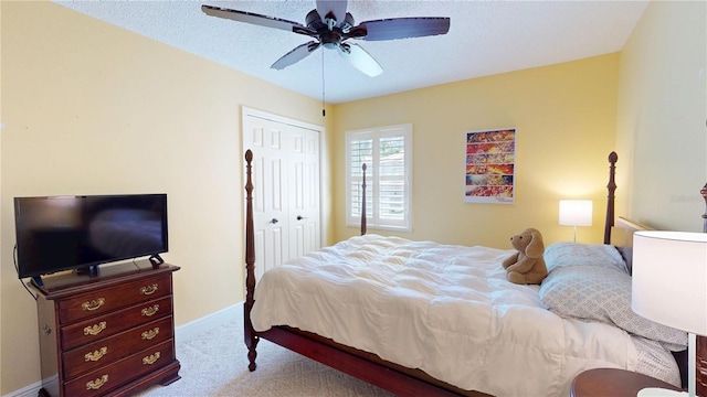 carpeted bedroom featuring a closet, a textured ceiling, baseboards, and a ceiling fan