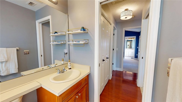 bathroom featuring vanity, wood finished floors, visible vents, and baseboards