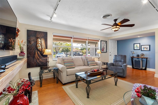 living room with visible vents, rail lighting, baseboards, and wood finished floors