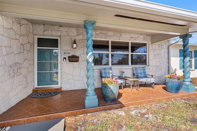 doorway to property with covered porch and stone siding