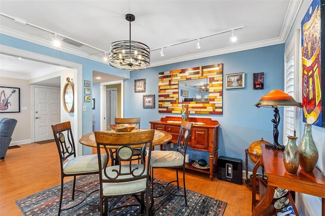 dining space featuring visible vents, crown molding, baseboards, an inviting chandelier, and wood finished floors