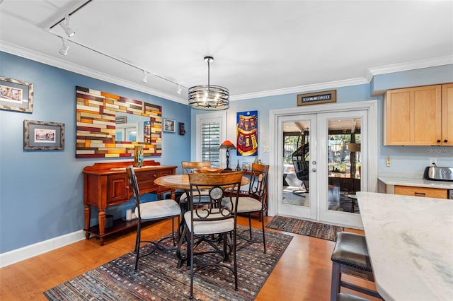 dining space featuring baseboards, ornamental molding, french doors, light wood-type flooring, and a chandelier