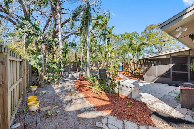 view of yard featuring a patio area, a fenced backyard, and a sunroom