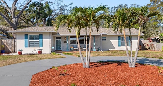 single story home with stucco siding, driveway, a front yard, and fence