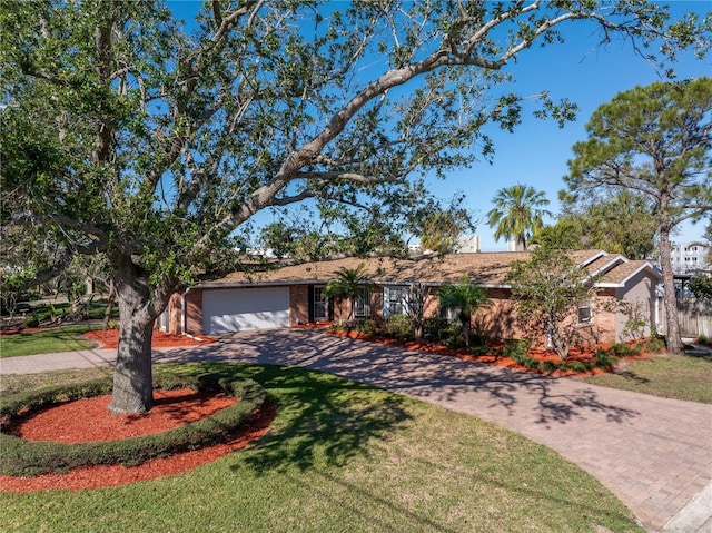 ranch-style home with brick siding, decorative driveway, an attached garage, and a front lawn