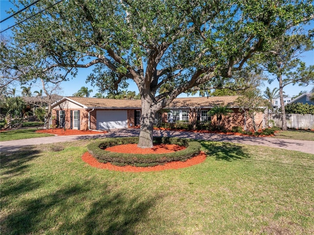 ranch-style home with driveway, fence, a front yard, a garage, and brick siding