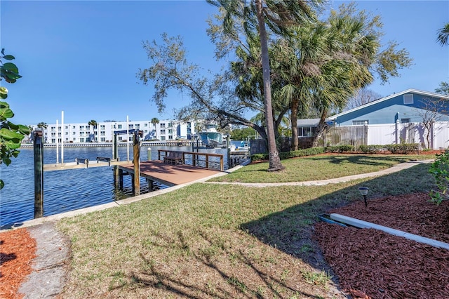 view of dock with boat lift, a water view, a yard, and fence