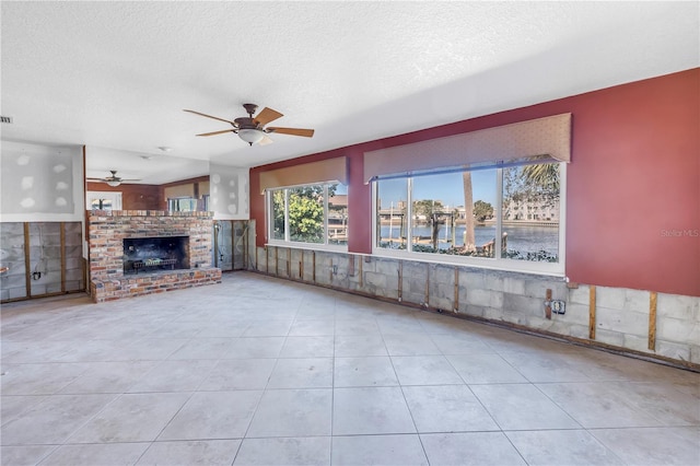 unfurnished living room featuring tile patterned floors, a fireplace, a textured ceiling, and ceiling fan