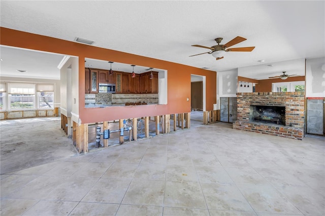 unfurnished living room featuring a brick fireplace, light tile patterned floors, a ceiling fan, and visible vents