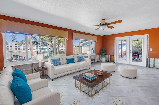 living area featuring a wealth of natural light, french doors, a textured ceiling, and a ceiling fan