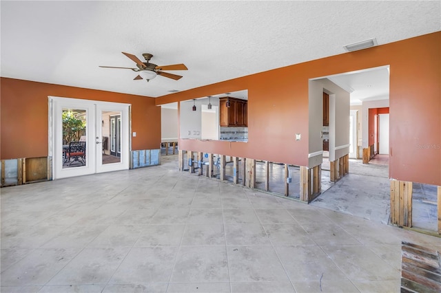 unfurnished living room featuring visible vents, french doors, a textured ceiling, and ceiling fan