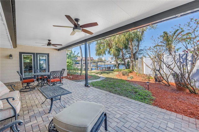 view of patio with a ceiling fan, outdoor dining area, and fence