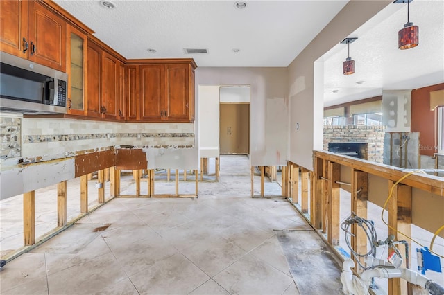 kitchen with visible vents, decorative light fixtures, stainless steel microwave, tasteful backsplash, and glass insert cabinets