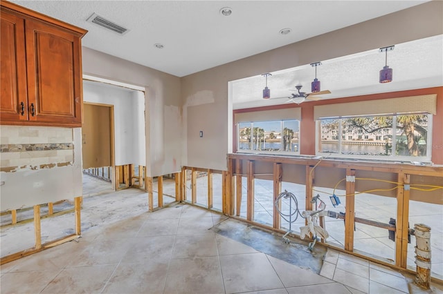 corridor featuring light tile patterned flooring, visible vents, and a textured ceiling