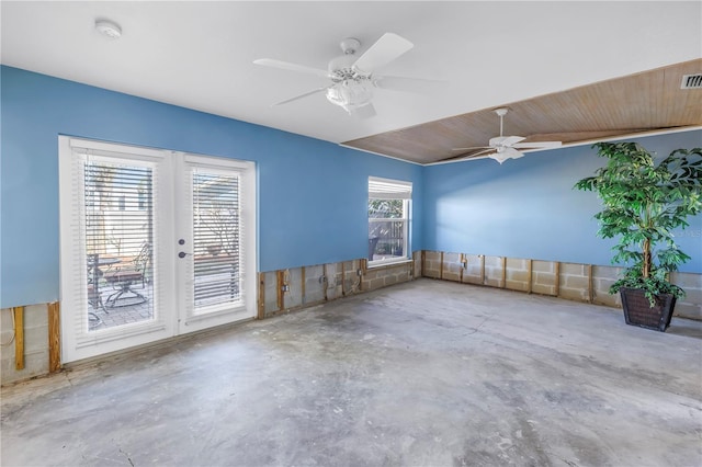 spare room featuring unfinished concrete flooring, a ceiling fan, visible vents, and french doors