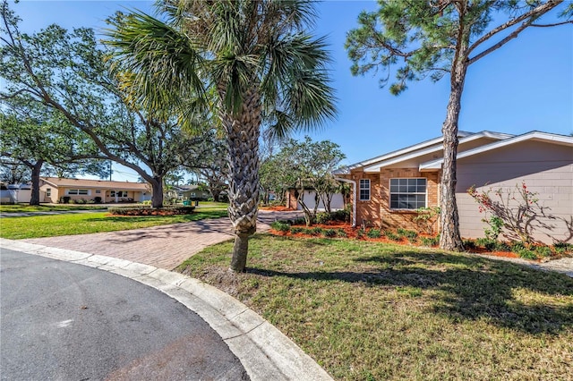 view of front of house with a front lawn, decorative driveway, brick siding, and an attached garage