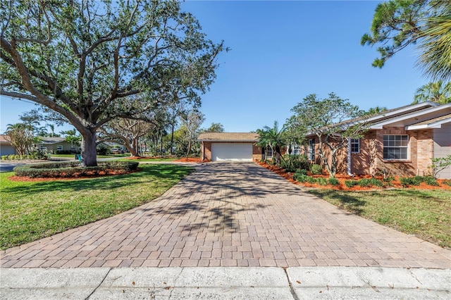 view of front facade with decorative driveway, a front yard, a garage, and brick siding